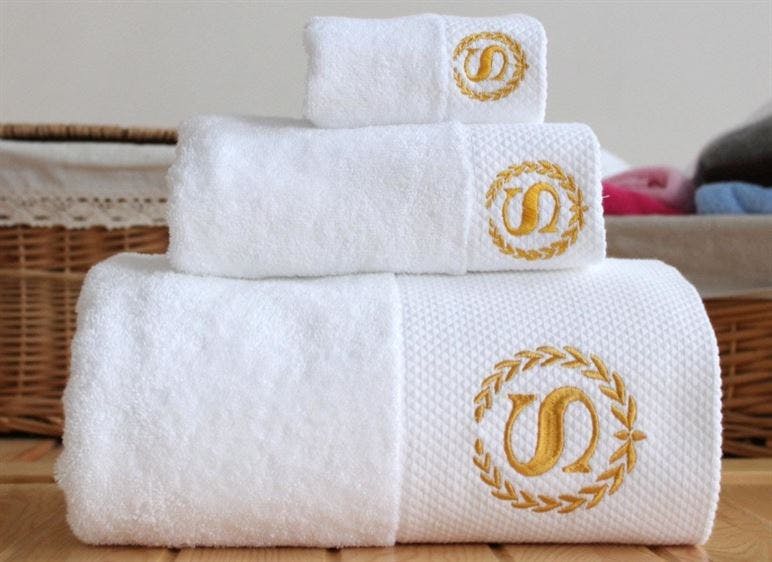Stack of white towels with monogram of letter S surrounded by a wreath.